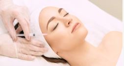 woman lying down with eyes closed while receiving a skin booster treatment injection at an aesthetic clinic